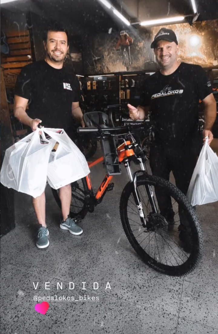 Cliente com mountain bike azul equipada com cadeirinha infantil