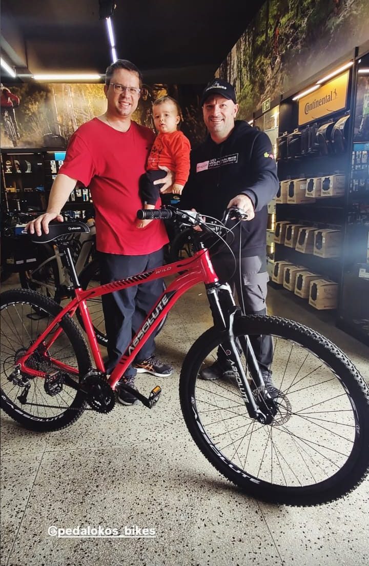 Cliente recebendo mountain bike Absolute vermelha na loja Pedalokos